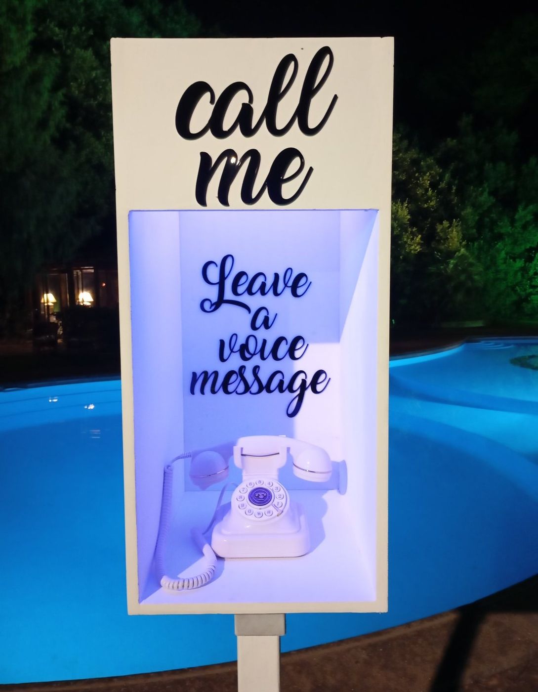 Telefono vintage bianco con insegna Call me a bordo piscina