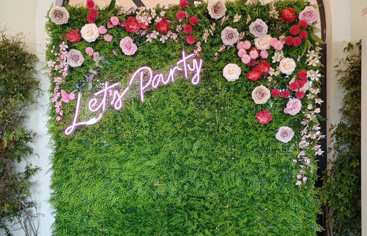Parete verde con fiori e scritta al neon
